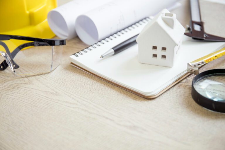 plans, loupe, casque de chantier, lunettes de protections sur une table