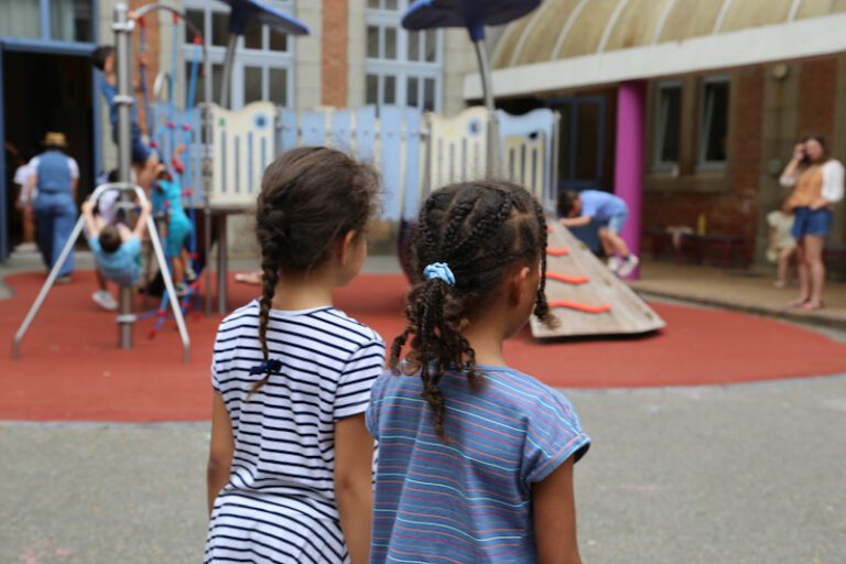 deux jeunes filles de dos dans leur cour d'école. Structure de jeux en arrière plan